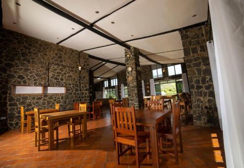uma sala de jantar com mesas e cadeiras de madeira em Imbogo Diners and Lounge em Kisoro