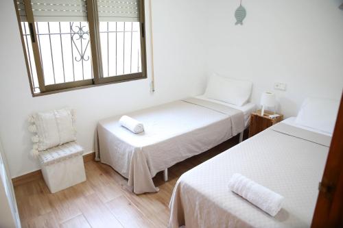 Cette chambre dispose de deux lits, d'une chaise et d'une fenêtre. dans l'établissement Casa de playa, cerca de todo, à Los Narejos