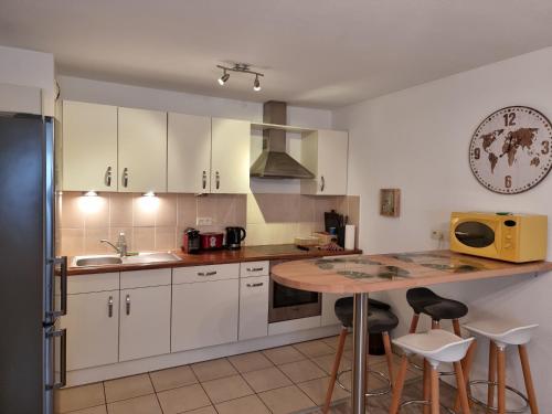 a kitchen with white cabinets and a table with stools at Résidence Villa d'Ambre in Colmar