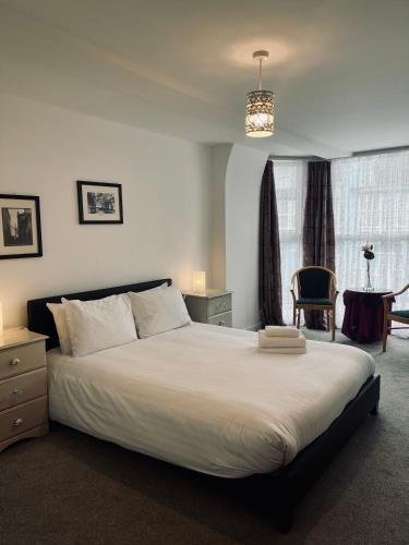 um quarto com uma grande cama branca e uma cadeira em One bedroom apartment, no 4 em Ilfracombe