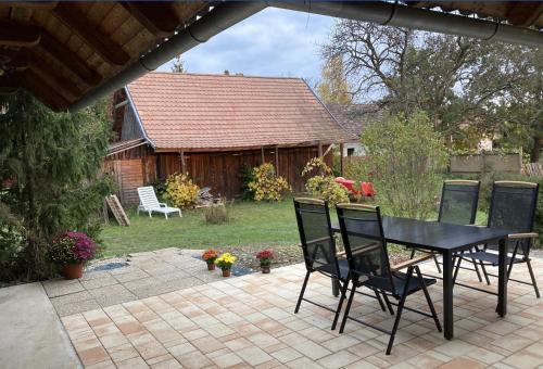a patio with a black table and chairs in a yard at Naturpark Ferienhaus in Szalafő