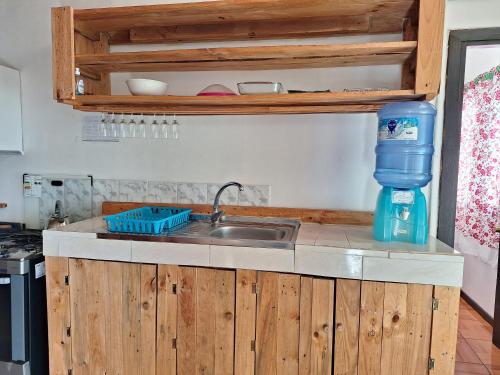 a kitchen with a sink and a water bottle on a counter at Cabañas puna poho in Hanga Roa