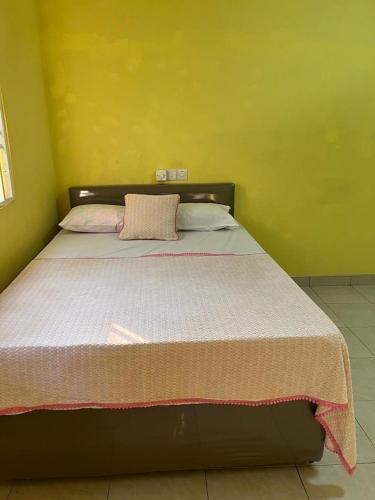 een bed in een kamer met een gele muur bij Mary’s Residence in Accra