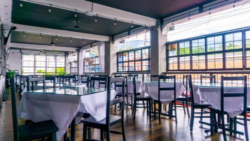 un comedor con mesas, sillas y ventanas en Hotel Villa Antigua en San Salvador