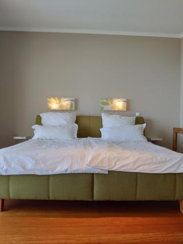 a bed with white sheets and two lights on it at 17 ° West, Lux. Inf. Pool villa, 5 minutes to the sandy beach, WiFi in Estreito da Calheta