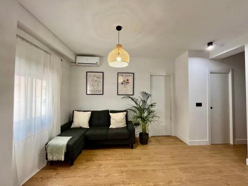 Piso Picasso, Modern Apartment in the Heart of Malaga City في مالقة: غرفة معيشة مع أريكة ونبات الفخار