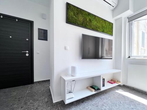 ein Wohnzimmer mit einem TV an einer weißen Wand in der Unterkunft D1STUDIO στην Πάτρα in Patras