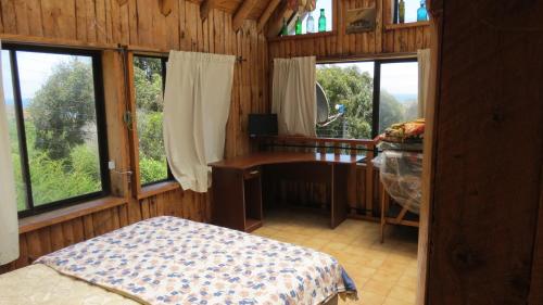 een slaapkamer met een bureau in een houten kamer met ramen bij Casa Rustica a pasos de la playa in El Quisco