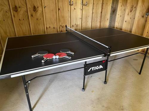 a ping pong table with two ping pong rackets at Old Town Bay St. Louis Outdoor Bar Area Game Room in Bay Saint Louis
