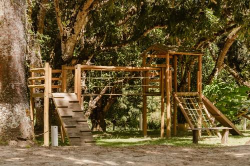 a wooden playground in front of a tree at Villa Nova Holanda in Mulungu