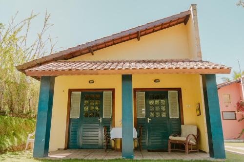 a small yellow house with blue doors and a table at Villa Nova Holanda in Mulungu