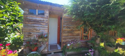 une petite maison en bois avec une porte et des fleurs dans l'établissement Pieza y estacionamiento independiente, à Panguipulli