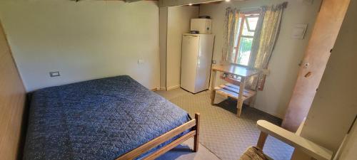 um pequeno quarto com uma cama e um frigorífico em Pieza y estacionamiento independiente em Panguipulli