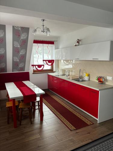 eine Küche mit roten und weißen Schränken und einem Tisch in der Unterkunft Willa u Bacy in Leśnica