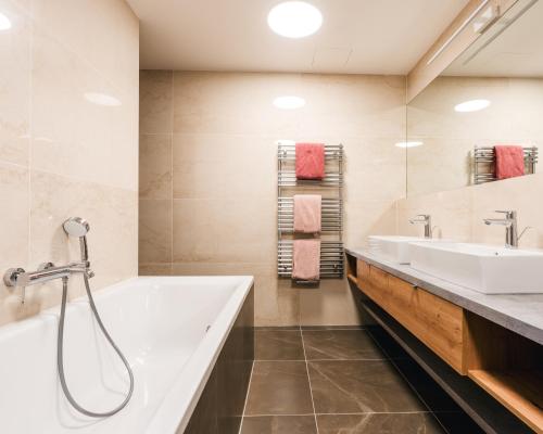 La salle de bains est pourvue de 2 lavabos et d'une baignoire. dans l'établissement Molo Lipno resort luxusní apartmán 4kk, à Český Krumlov