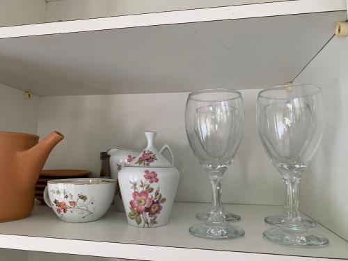 drei Weingläser und eine Vase auf einem Regal in der Unterkunft Apartamento Vista Mar in Peruíbe