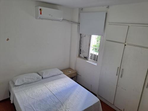 a small white room with a bed and a window at Quarto Familiar Aconchegante in Recife
