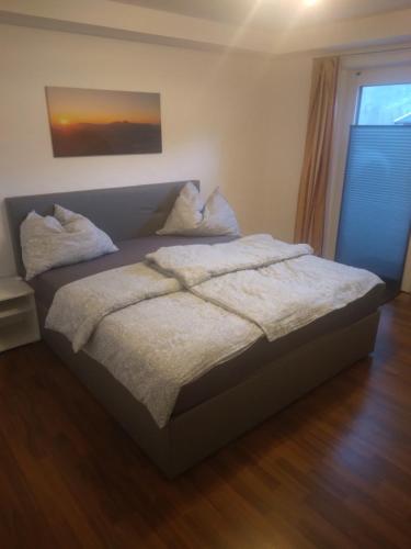 ein Bett mit weißer Bettwäsche und Kissen in einem Schlafzimmer in der Unterkunft Ferienwohnung Anton in Lofer