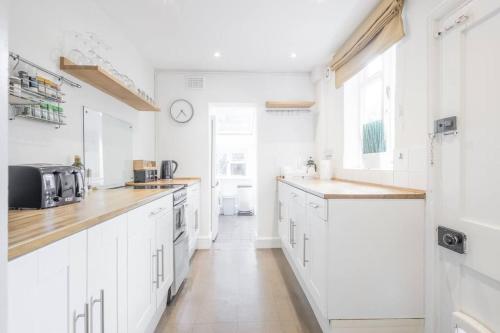 a white kitchen with white cabinets and a sink at Lovely 2 bedroom house in Cambridge (sleeps 4) in Cambridge