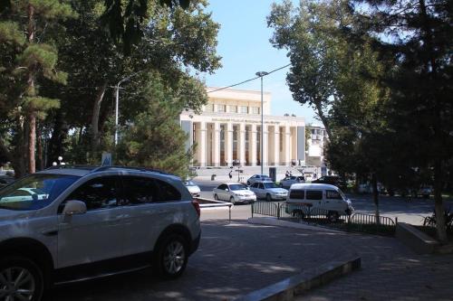 um carro estacionado num parque de estacionamento em frente a um edifício em Samarkand Central Apartments em Samarcanda