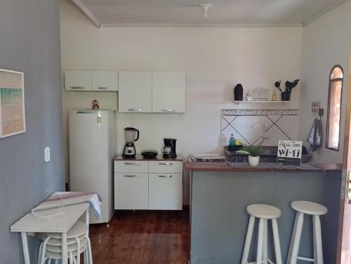 a kitchen with white cabinets and stools in it at Casa com vista para o mar em Paraty in Paraty
