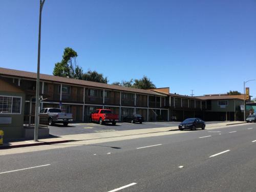 ein Gebäude mit Autos, die an der Straßenseite geparkt sind in der Unterkunft Ritz Inn-San Francisco Airport SFO in San Bruno