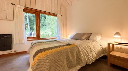 1 dormitorio con cama y ventana grande en Casa Chucao en Villa La Angostura