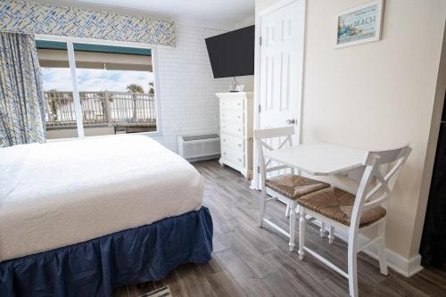 a bedroom with a bed and a desk and a window at King Bed Ocean View 2nd Floor in Pawleys Island
