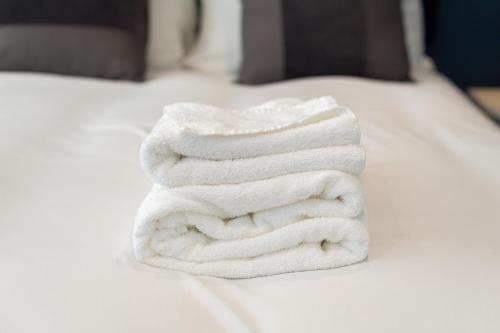 a stack of white towels sitting on a bed at Modern 4-Bed Retreat with Garden in Manchester