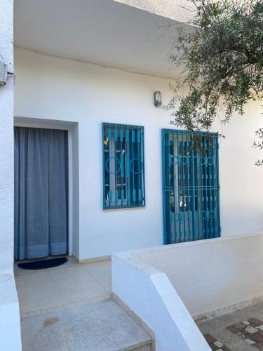 a white building with blue doors and a window at Résidence sassi in Nabeul