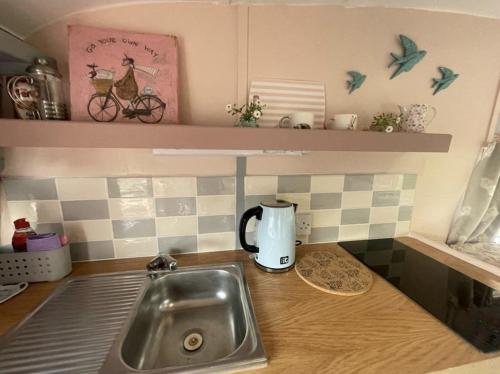 um balcão de cozinha com um lavatório e comodidades para preparar café em Molly The Vintage Caravan. em Wigton