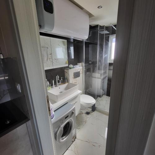 a bathroom with a sink and a washing machine at Luksuzni Apartman Harmonija Paralija in Paralia Katerinis