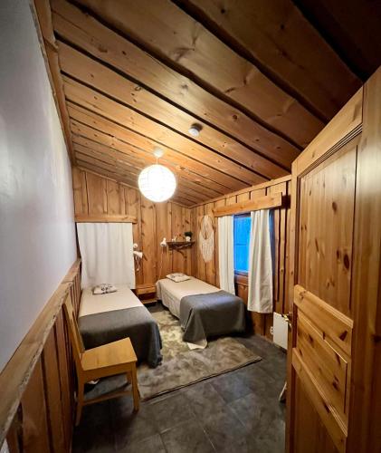 two beds in a room with wooden walls at Mäntyharju-mökki in Syöte