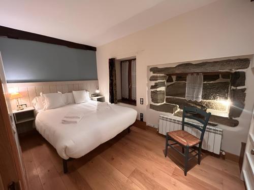 a bedroom with a large white bed and a chair at Apto ElizaG-1 in Lesaka