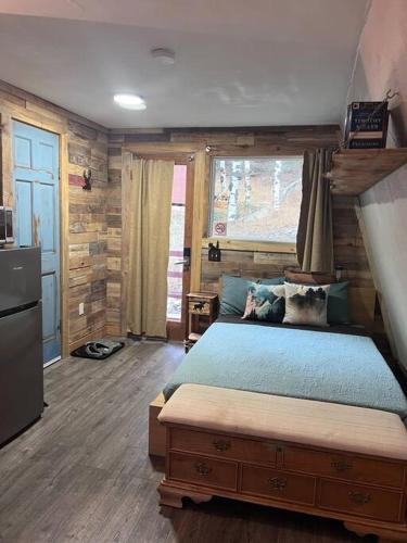 a bedroom with a blue bed and a kitchen at Cozy Cabin in Florissant