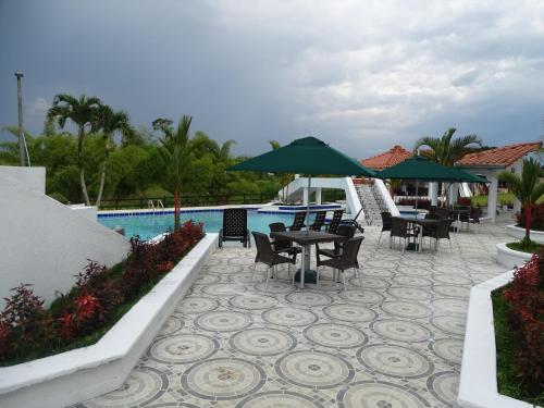 Playa Verde的住宿－Hotel Palmas De Alcalá，游泳池旁带桌子和遮阳伞的天井