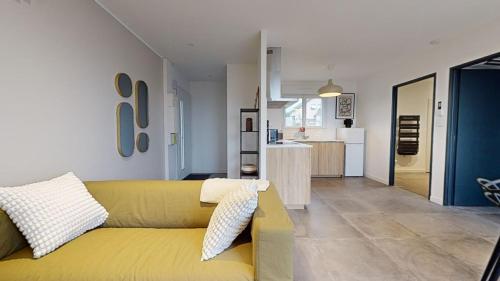 un salon avec un canapé jaune et une cuisine dans l'établissement Le Petit Vernois - Appartement avec Terrasse !, à Dole