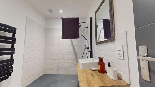 Baño blanco con lavabo y espejo en Le Petit Vernois, en Dole