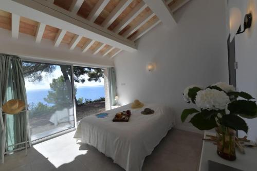 Cette chambre blanche dispose d'un lit et d'une grande fenêtre. dans l'établissement Villa 6 chambres, vue mer sur 180°,plage privée., à Cavalaire-sur-Mer