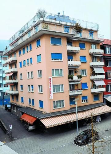 un grand bâtiment rose avec balcon dans une rue dans l'établissement Hotel Restaurant Krebs, à Granges