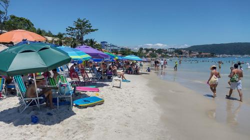 eine Gruppe von Menschen, die am Strand mit Sonnenschirmen sitzen in der Unterkunft Residencial Atalanta in Bombinhas