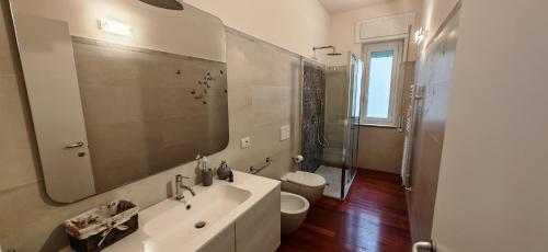 Un baño con lavabo, inodoro y espejo. en Casa Di Ariel, en La Spezia