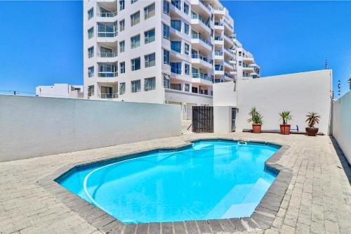 a swimming pool in front of a tall building at 605 Nautica in Bloubergstrand