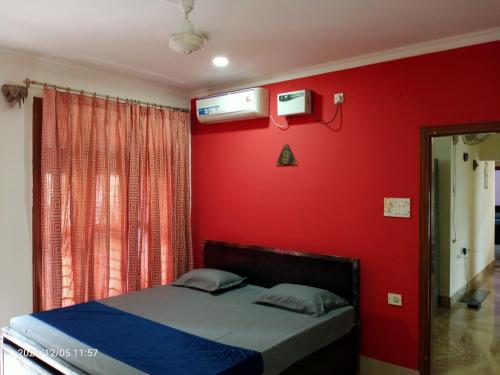 a bedroom with a red wall with a bed in it at LOZZY HOMESTAY in Guwahati