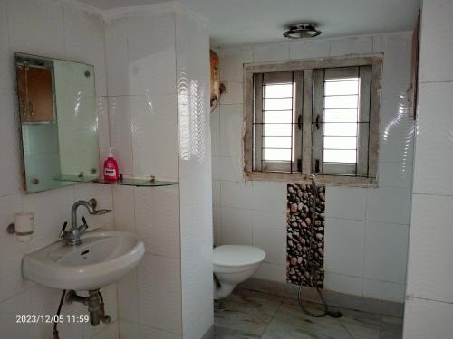 a bathroom with a sink and a toilet and a window at LOZZY HOMESTAY in Guwahati
