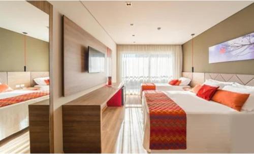 um quarto grande com 2 camas e uma televisão em Hotel Laghetto Stilo Borges em Gramado