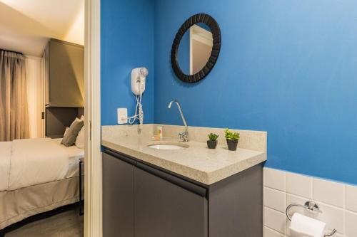 a bathroom with a sink in a room with a bed at Duque by My Way - 100 meters from Santa Casa and UFRGS in Porto Alegre