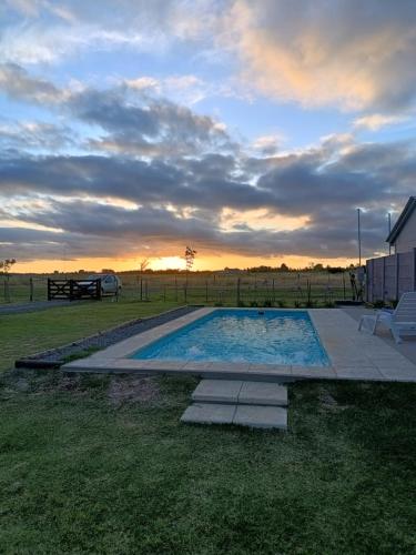 a swimming pool with a sunset in the background at Cabañas Las Escondidas in Chascomús