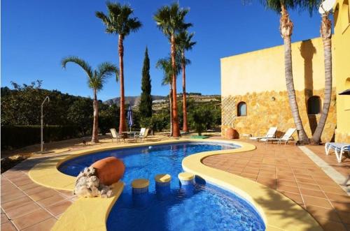 ein Pool mit Palmen und ein Gebäude in der Unterkunft Casa Rural Planet in Bolulla