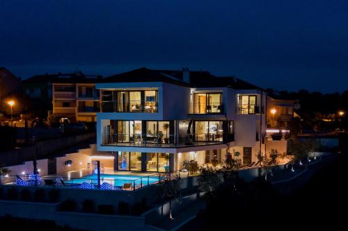 a large house with a swimming pool at night at The Grand View Villa in Njivice